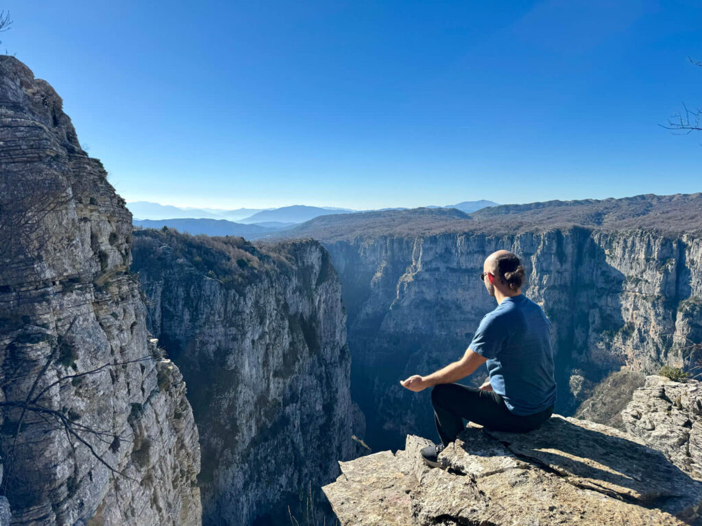 Man sitting at the edge of Vikos Gorge