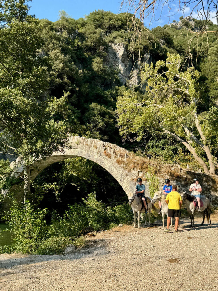 Horseback riding next to a stone bridge