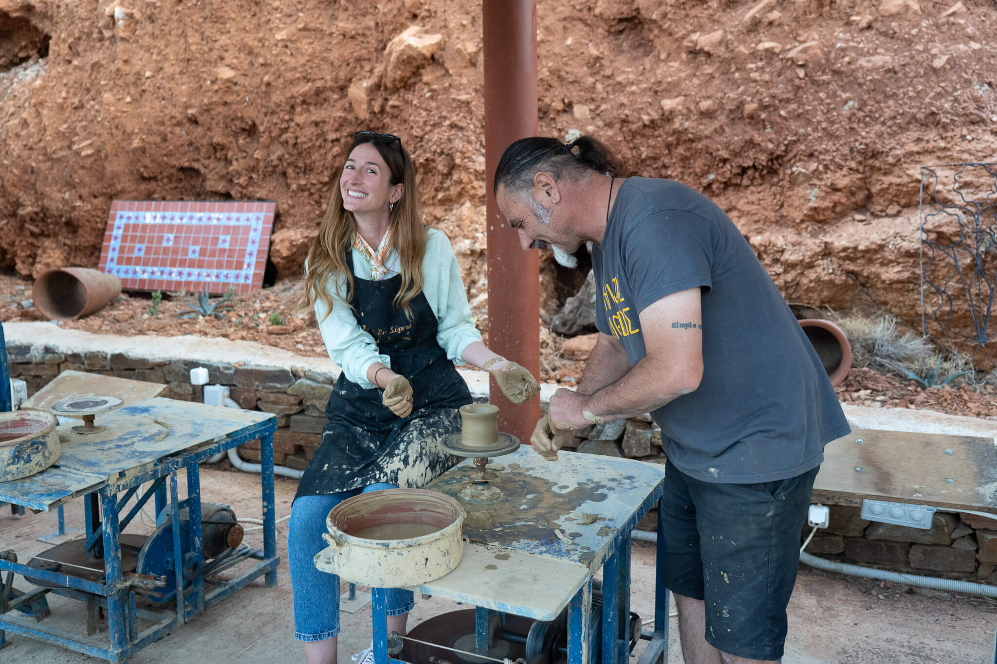 A potter assists a traveler with the clay